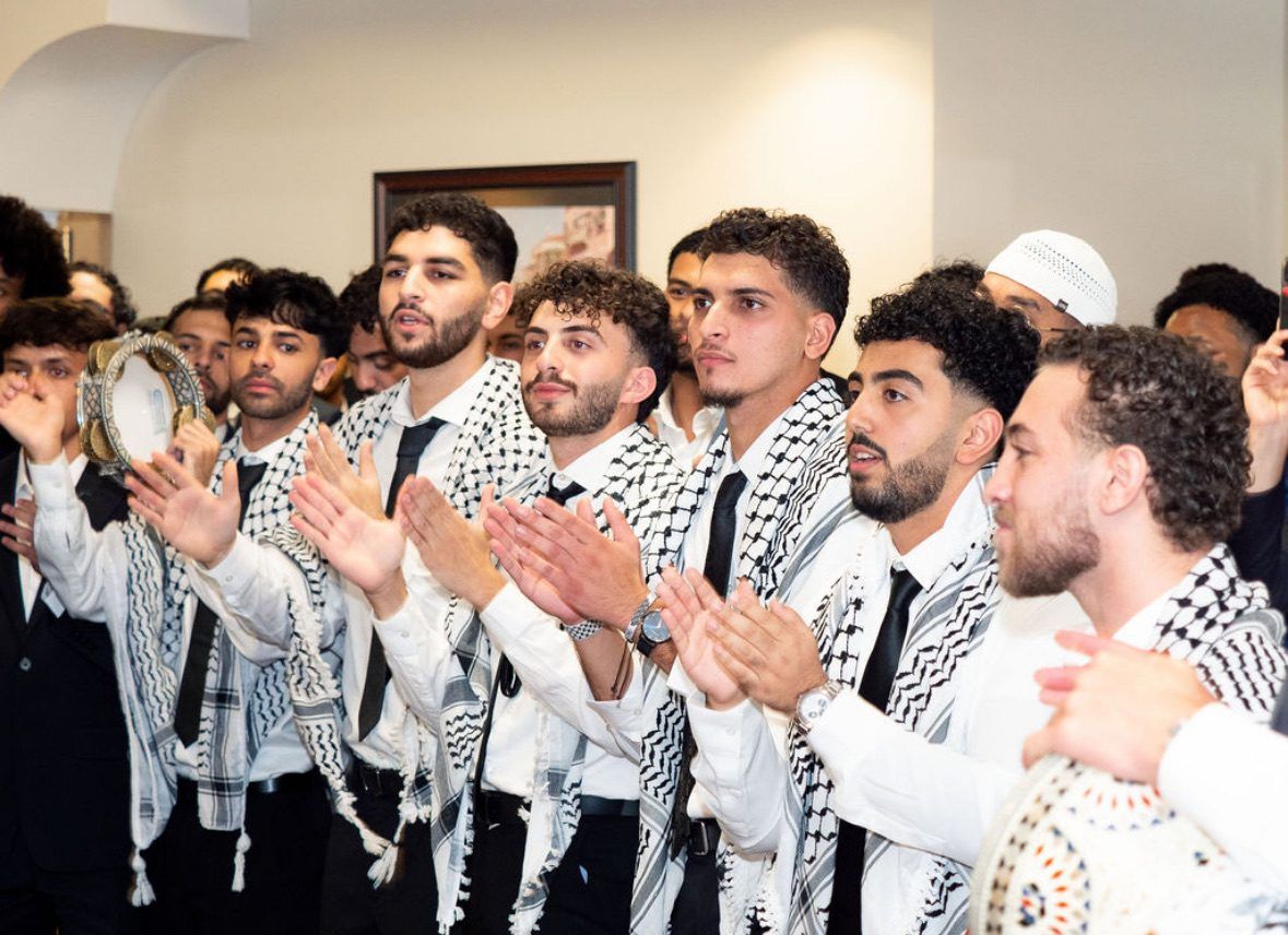 Hayat Al-Dabka dancers in keffiyehs clapping in a line at a wedding, North Carolina